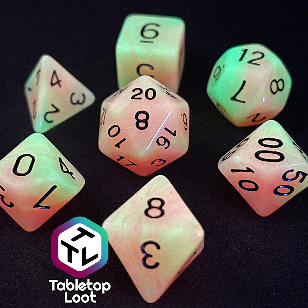 The Nuclear glow in the dark 7 piece dice set from Tabletop Loot with swirls of orange and yellow glow pigment and black numbering, shown glowing.