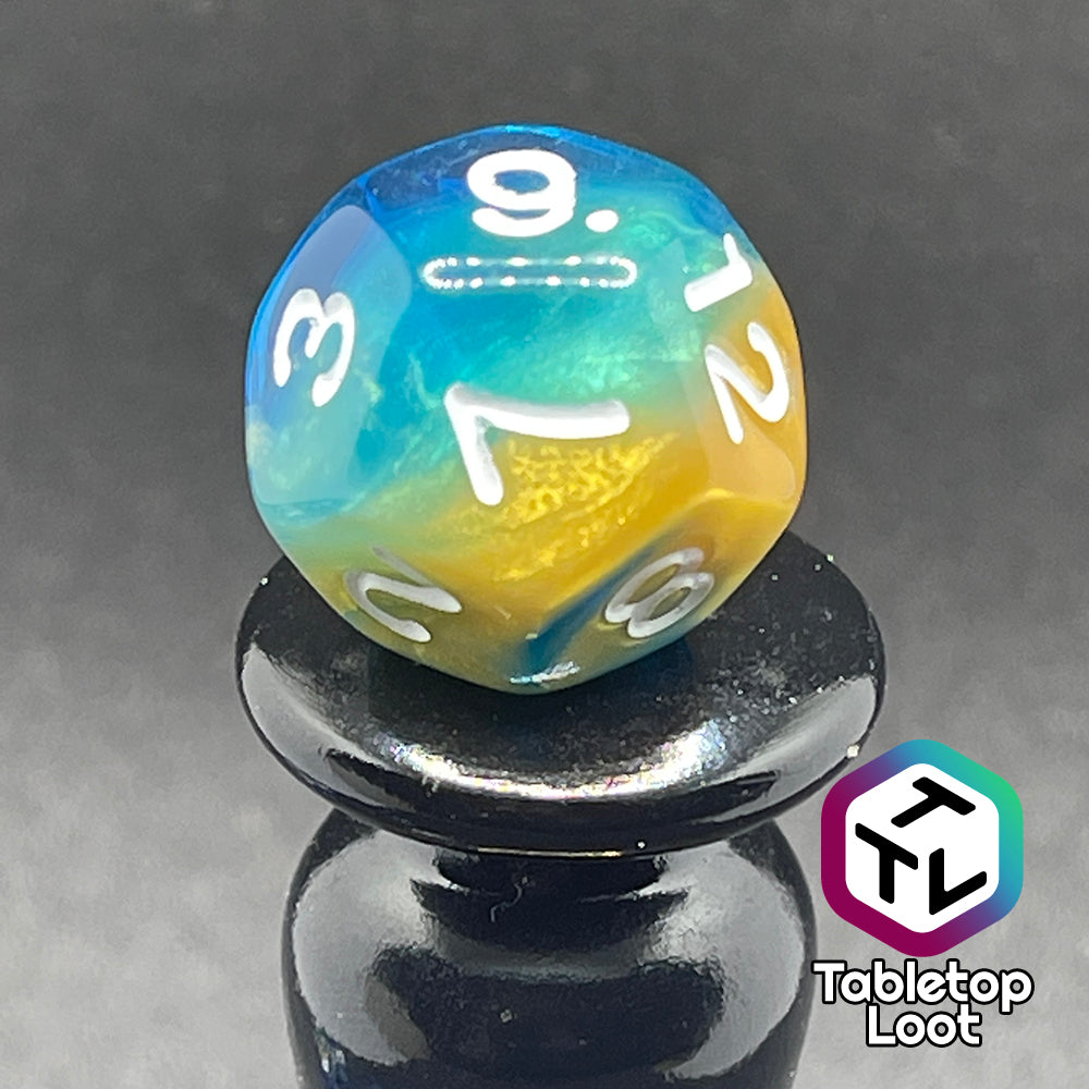 A close up of the D12 from the Oceanside 7 piece dice set from Tabletop Loot with swirls of glittery yellow and blue suspended in clear acrylic with white numbering.
