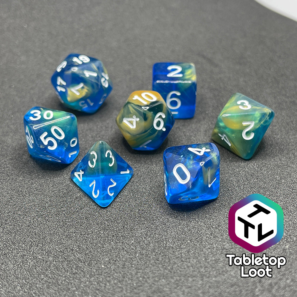 The Oceanside 7 piece dice set from Tabletop Loot with swirls of glittery yellow and blue suspended in clear acrylic with white numbering.