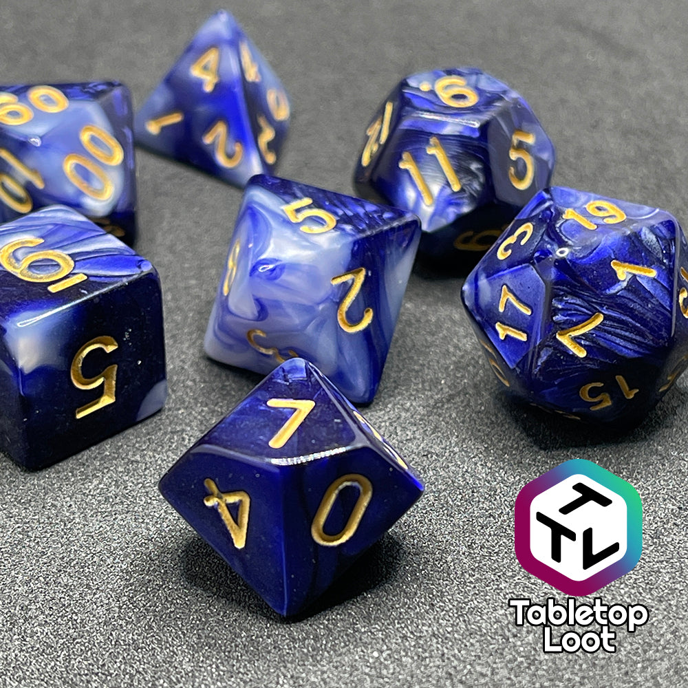 A close up of the Order of the Night's Veil 7 piece dice set from Tabletop Loot with swirls of pearlescent purple and white with gold numbering.
