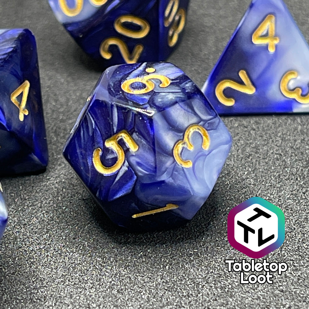A close up of the D12 from the Order of the Night's Veil 7 piece dice set from Tabletop Loot with swirls of pearlescent purple and white with gold numbering.