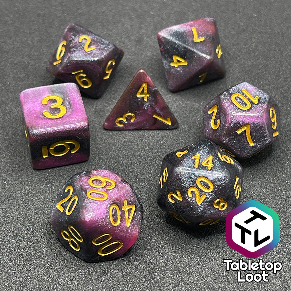 The Orion Nebula 7 piece dice set from Tabletop Loot with swirls of pink and black, tons of glitter, and gold numbering.