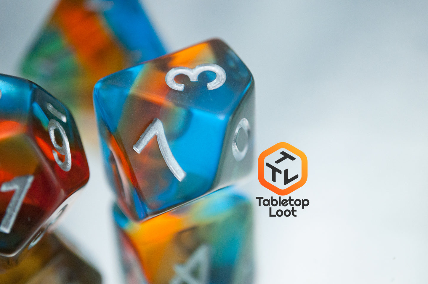 A close up of the D10 from the Parallel Universes 7 piece dice set from Tabletop Loot with an orange stripe in blue resin and silver numbering.