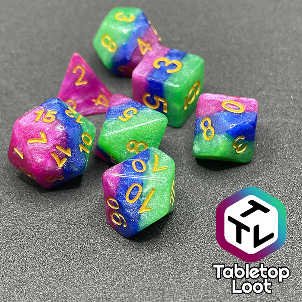 A close up of the Petit Fours 7 piece dice set from Tabletop Loot; layers of shimmering green, blue, and pink with gold numbering.