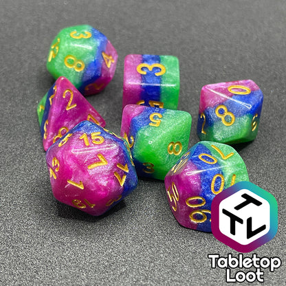 The Petit Fours 7 piece dice set from Tabletop Loot; layers of shimmering green, blue, and pink with gold numbering.