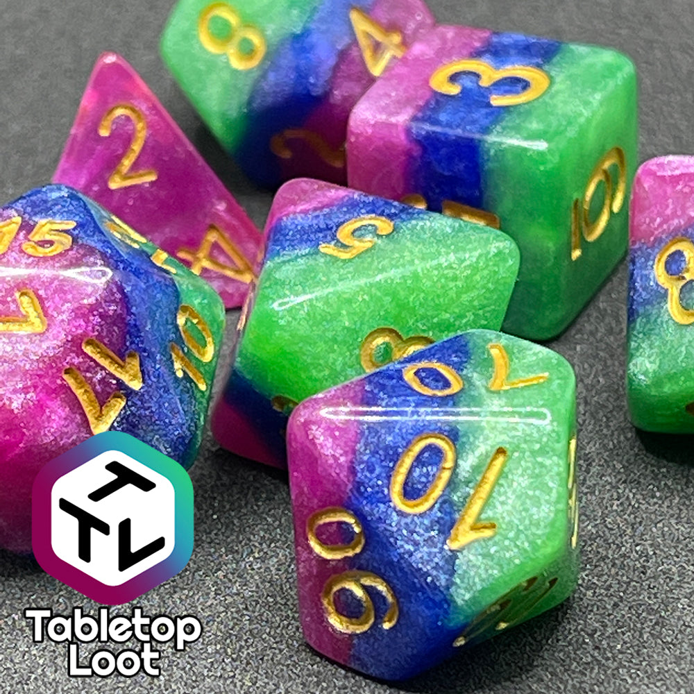 A close up of the Petit Fours 7 piece dice set from Tabletop Loot; layers of shimmering green, blue, and pink with gold numbering.