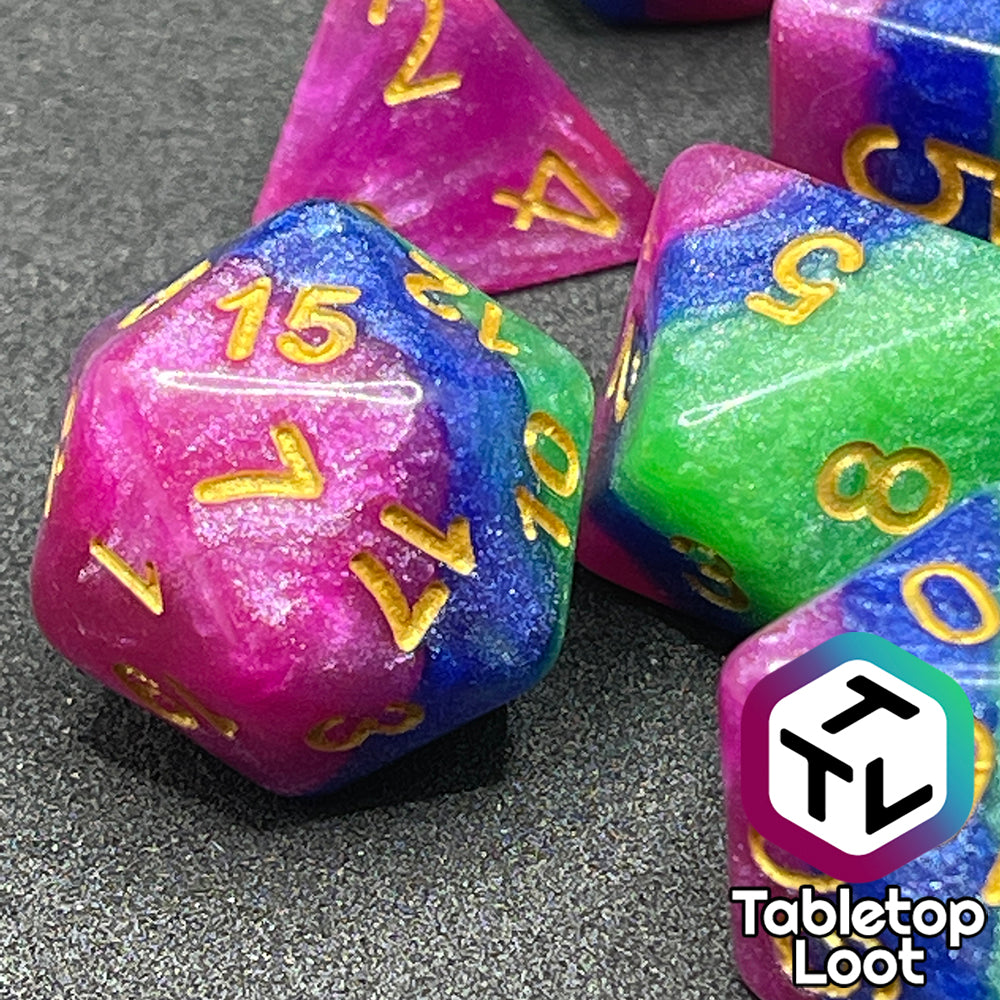 A close up of the D20 from the Petit Fours 7 piece dice set from Tabletop Loot; layers of shimmering green, blue, and pink with gold numbering.