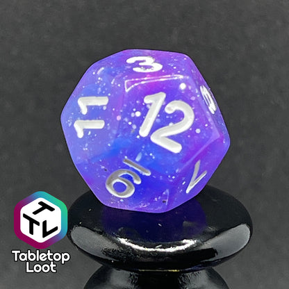 A close up of the D12 from the Phantasmal Force 7 piece dice set with swirls of blue and purple, lots of glitter, and white numbering.