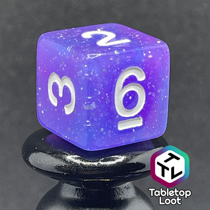 A close up of the D6 from the Phantasmal Force 7 piece dice set with swirls of blue and purple, lots of glitter, and white numbering.