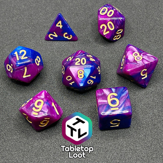 The Spelljammin' 7 piece dice set from Tabletop Loot with pearlescent swirls of purple and blue and gold numbering.