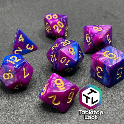 A close up of the Spelljammin' 7 piece dice set from Tabletop Loot with pearlescent swirls of purple and blue and gold numbering.