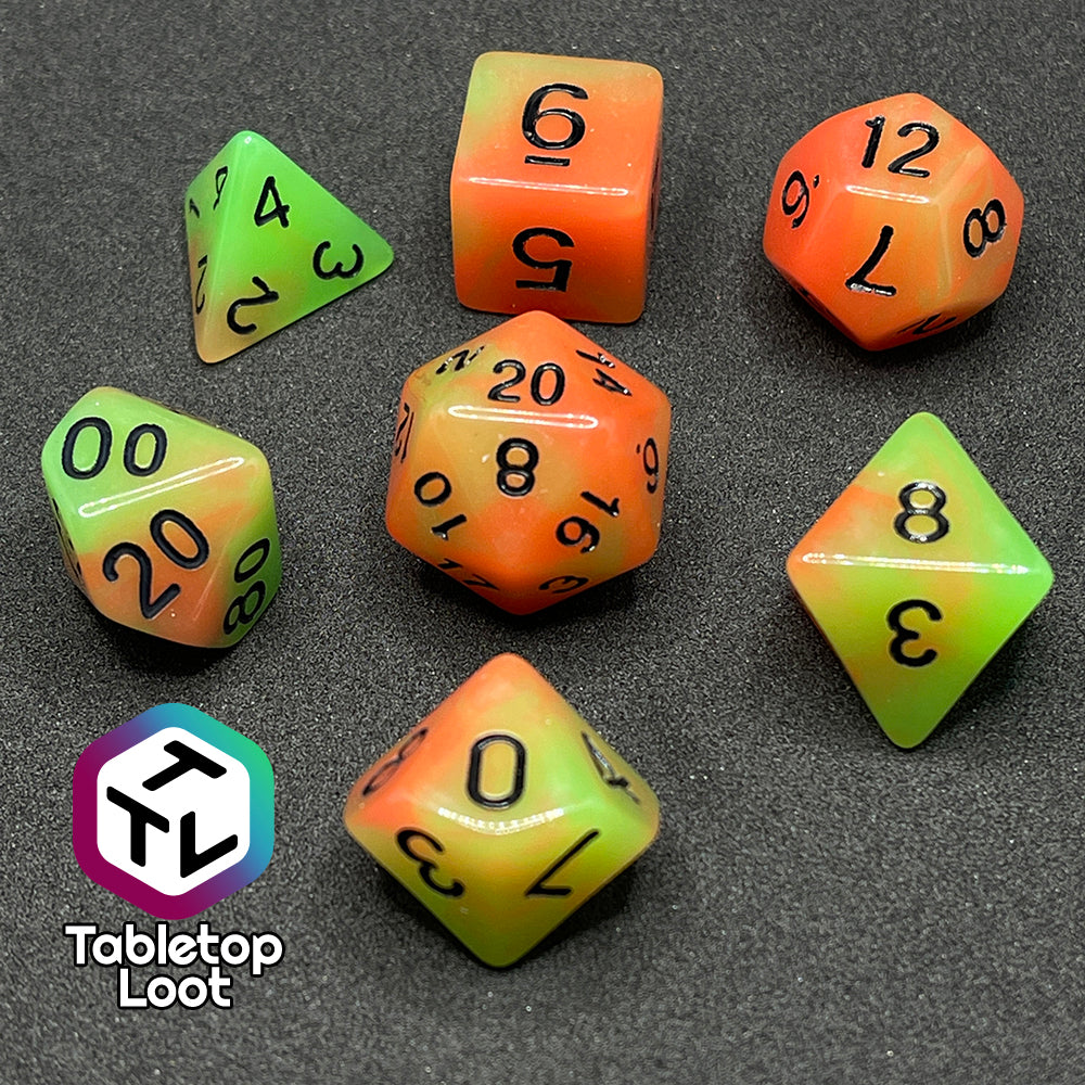 The Neon Nights glow in the dark 7 piece dice set from Tabletop Loot with swirled orange and yellow glow pigment and black numbering, shown in light.