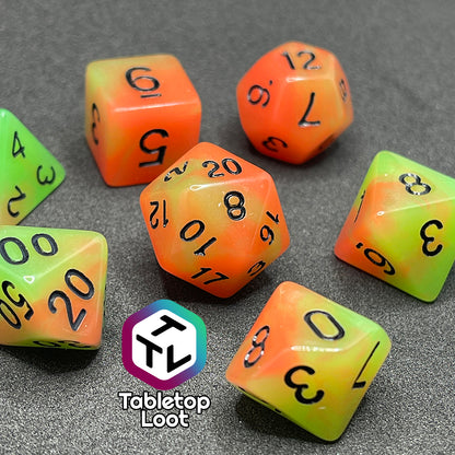 The Neon Nights glow in the dark 7 piece dice set from Tabletop Loot with swirled orange and yellow glow pigment and black numbering, shown in light.