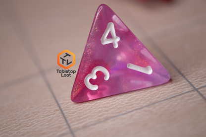 A close up of the D4 from the Pink Bunny 7 piece dice set from Tabletop Loot with yellow and gold shimmer in bright pink resin with white numbering.
