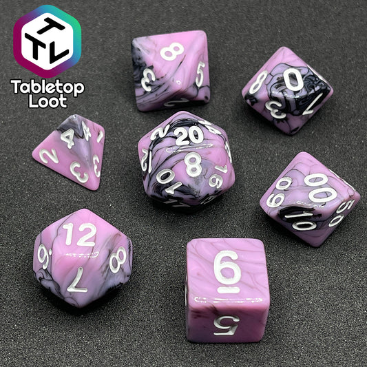The Pink Nightmare 7 piece dice set from Tabletop Loot with swirls of black in pink with white numbering.