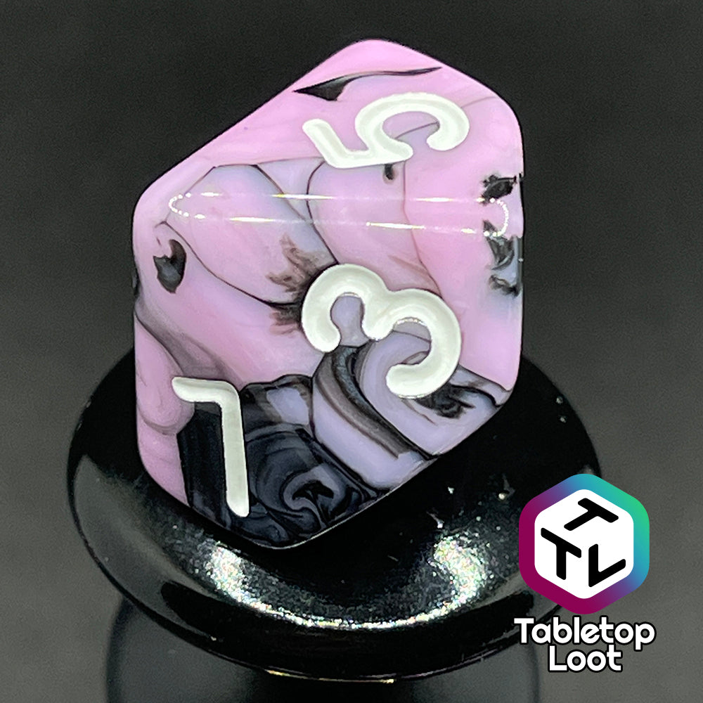 A close up of the D10 from the Pink Nightmare 7 piece dice set from Tabletop Loot with swirls of black in pink with white numbering.