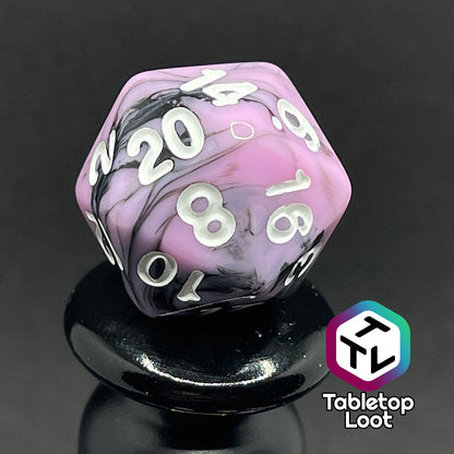 A close up of the D20 from the Pink Nightmare 7 piece dice set from Tabletop Loot with swirls of black in pink with white numbering.