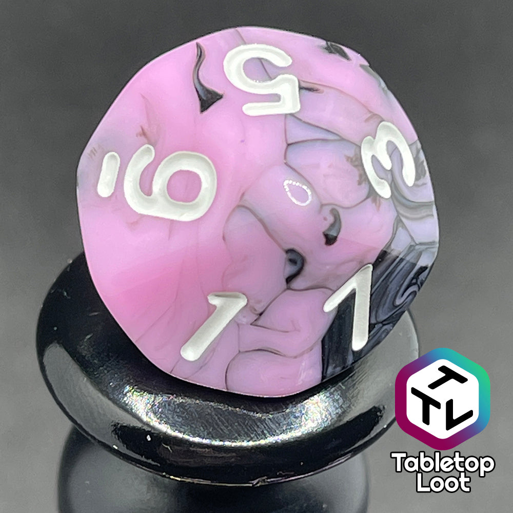 A close up of the D10 from the Pink Nightmare 7 piece dice set from Tabletop Loot with swirls of black in pink with white numbering.