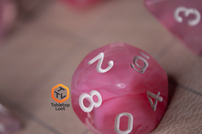 A close up of the D10 from the Pink Rose 7 piece dice set from Tabletop Loot with ribbons of pink in a clear resin with white numbering.