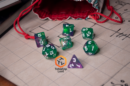 The Witch's Brew 7 piece dice set from Tabletop Loot with purple and green shimmery swirls and white numbering.