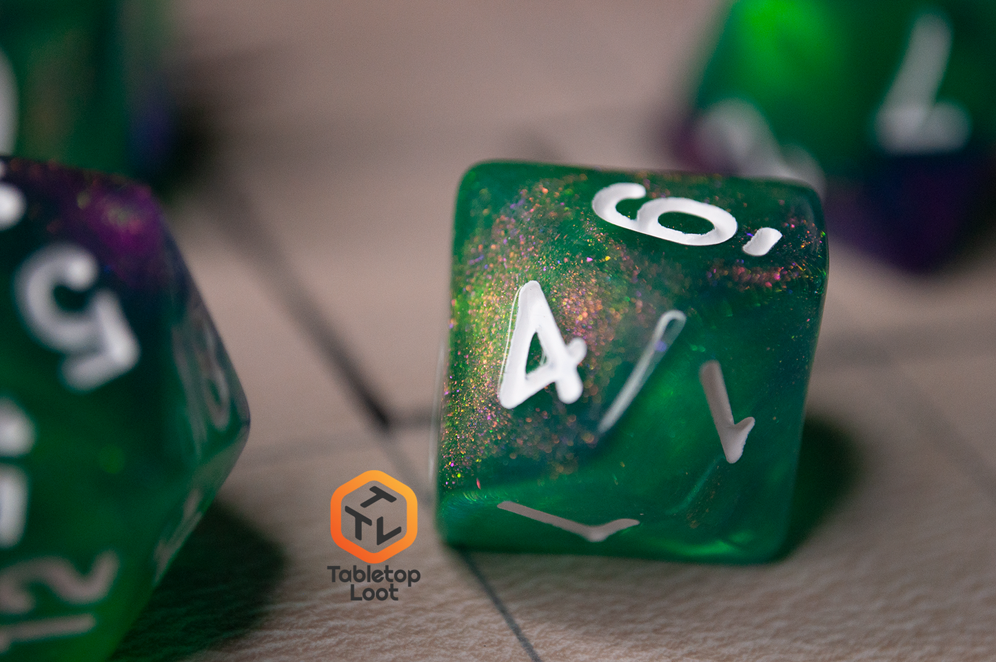A close up of the D10 from the Witch's Brew 7 piece dice set from Tabletop Loot with purple and green shimmery swirls and white numbering.