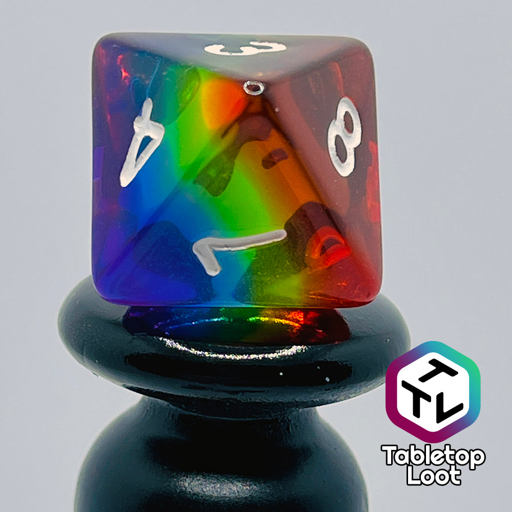 A close up of the D8 from the Pride 7 piece dice set from Tabletop Loot with stripes of translucent colors in rainbow order and white numbering.