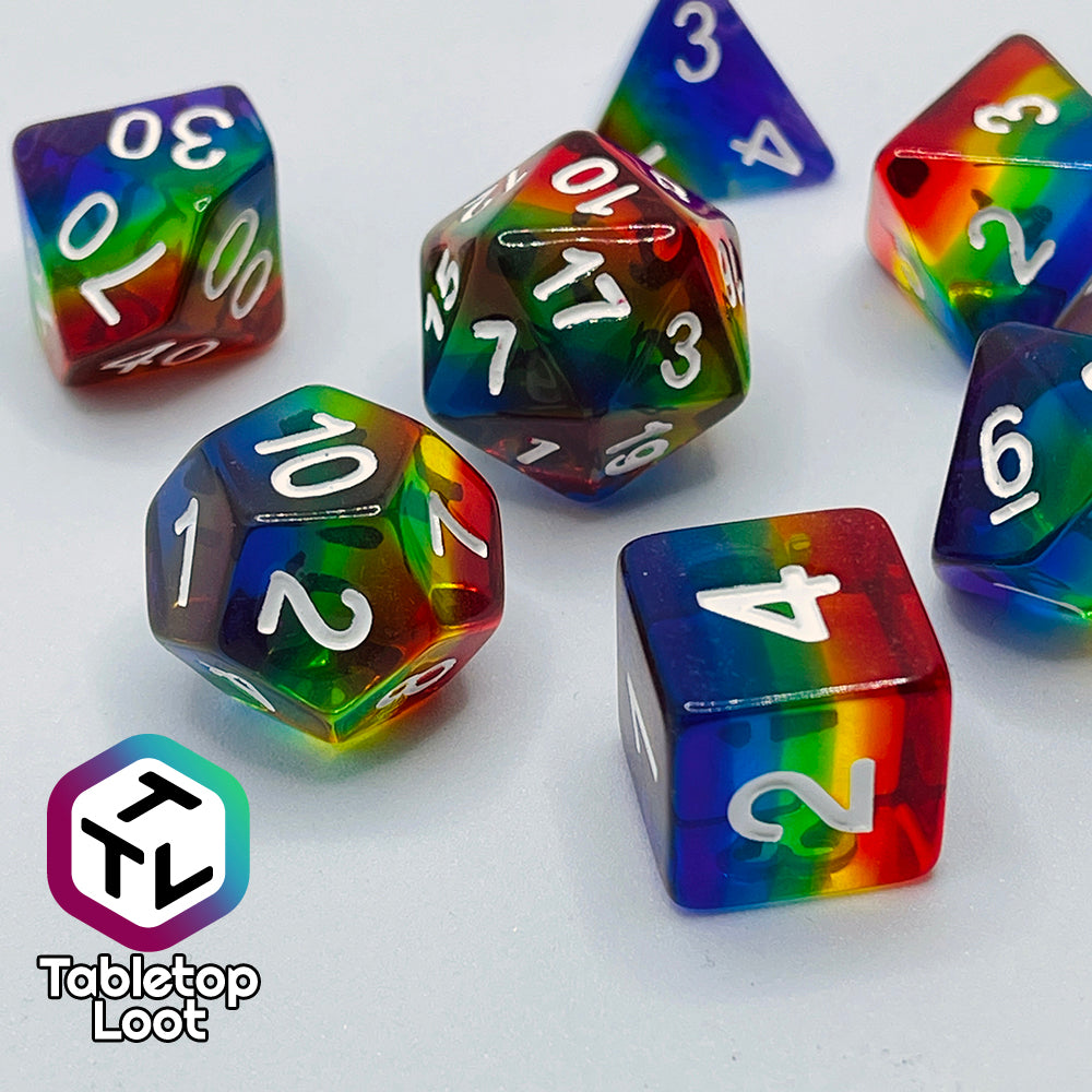 A close up of the Pride 7 piece dice set from Tabletop Loot with stripes of translucent colors in rainbow order and white numbering.