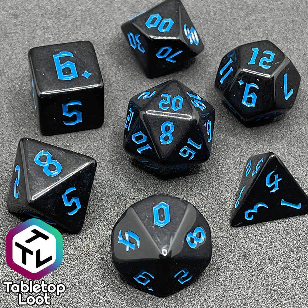 The Prime Directive 7 piece dice set from Tabletop Loot with bright blue bold gothic numbers on highly reflective black faces.