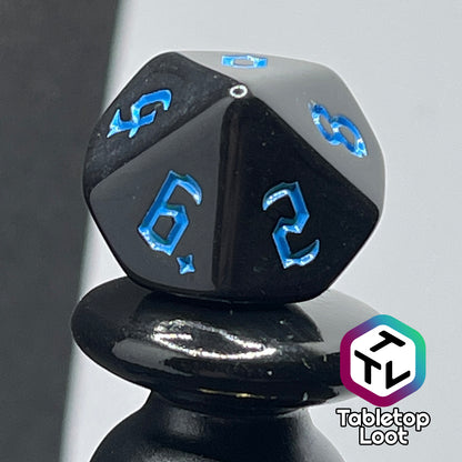 A close up of the D10 from the Prime Directive 7 piece dice set from Tabletop Loot with bright blue bold gothic numbers on highly reflective black faces.