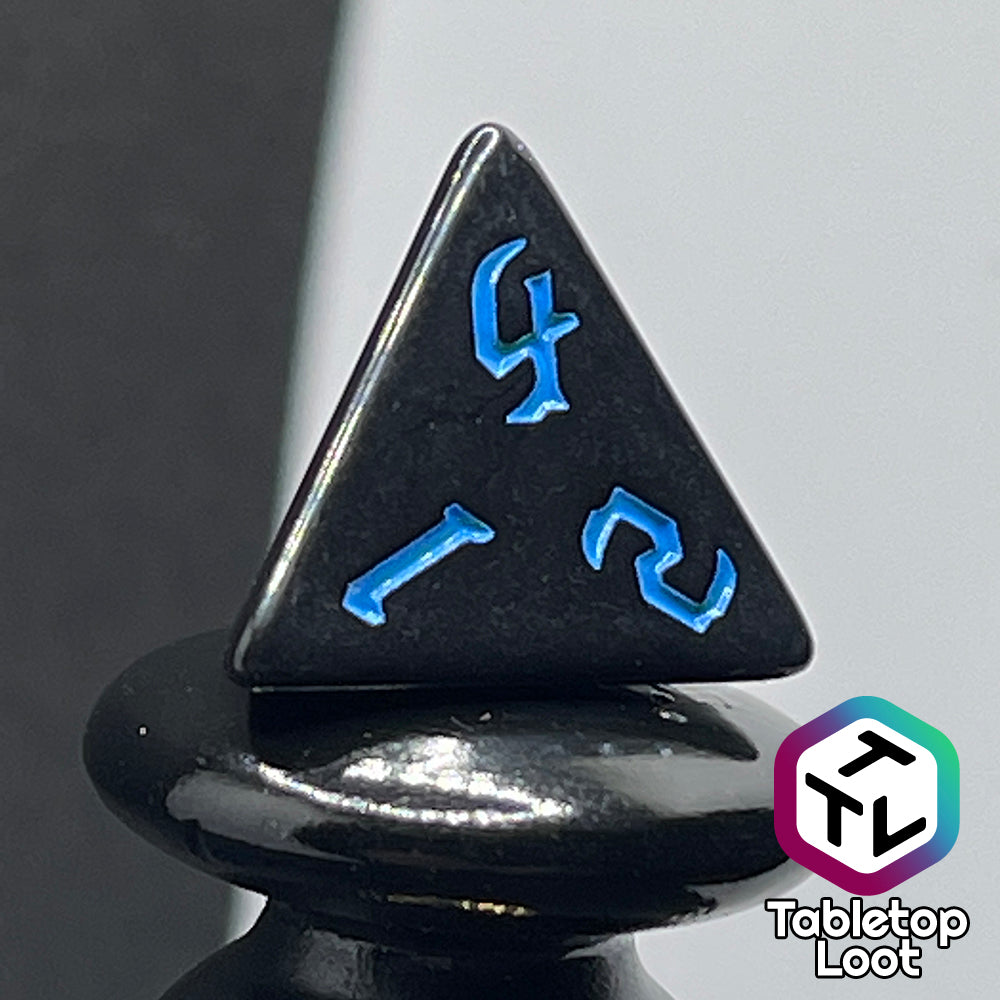 A close up of the D4 from the Prime Directive 7 piece dice set from Tabletop Loot with bright blue bold gothic numbers on highly reflective black faces.