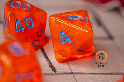 A close up of the D8 from the Radioactive Orange 7 piece dice set from Tabletop Loot with sparkly orange resin and bright blue numbering.