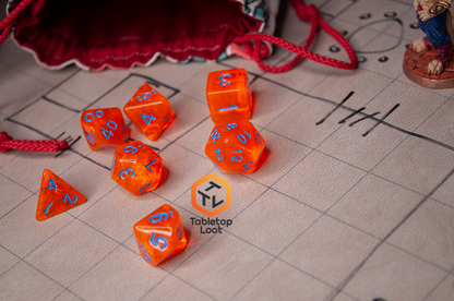 The Radioactive Orange 7 piece dice set from Tabletop Loot with sparkly orange resin and bright blue numbering.