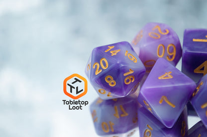 A close up of the Purple Jade 7 piece dice set from Tabletop Loot with swirled purple and white resin and gold numbering.