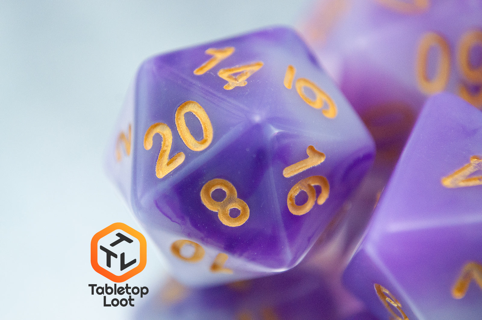 A close up of the D20 from the Purple Jade 7 piece dice set from Tabletop Loot with swirled purple and white resin and gold numbering.