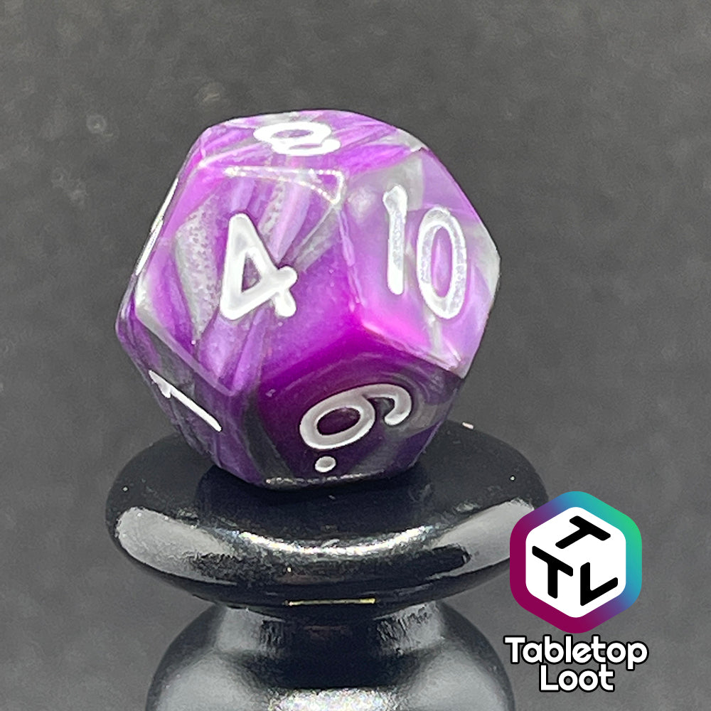 A close up of the D12 from the Purple Knight 7 piece dice set from Tabletop Loot with swirls of purple and pearlescent grey and white numbering.