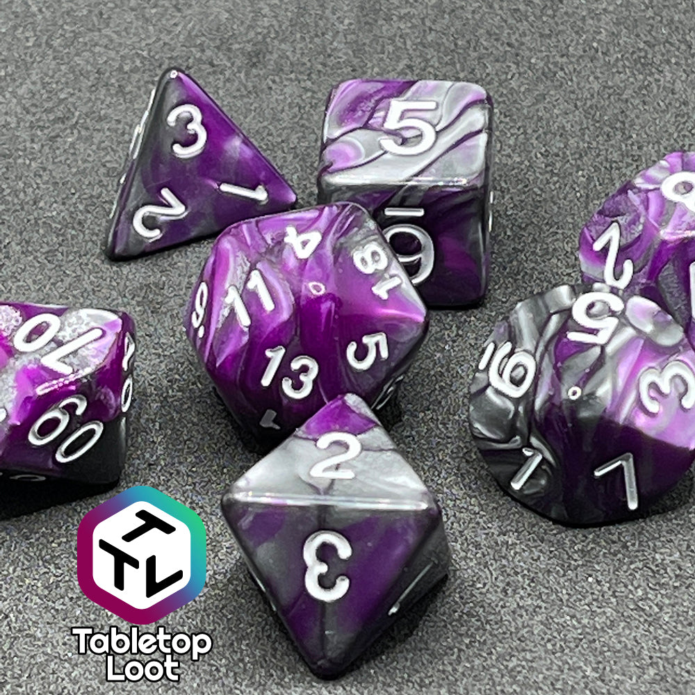 A close up of the Purple Knight 7 piece dice set from Tabletop Loot with swirls of purple and pearlescent grey and white numbering.