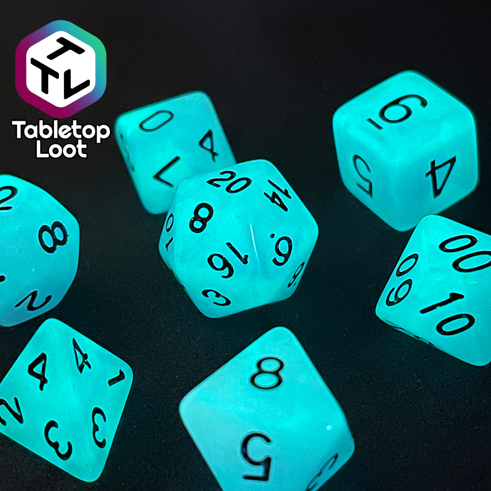 The Quantum 7 piece dice set from Tabletop Loot with swirls of blue and purple glow pigment and black numbering, shown glowing.