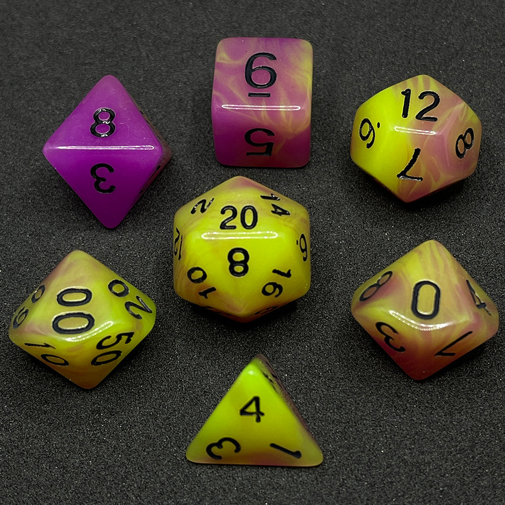 The Retro 80s glow in the dark 7 piece dice set from Tabletop Loot with swirls of pink and yellow glow pigment and black numbering, shown in light.