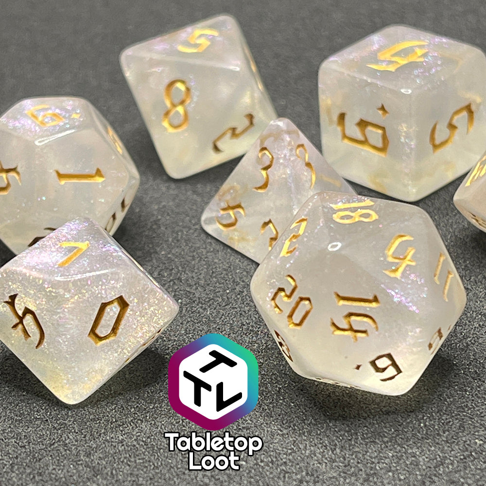 A close up of the Revivify 7 piece dice set from Tabletop Loot; semi-translucent dice with iridescent micro glitter and gold gothic numbering.