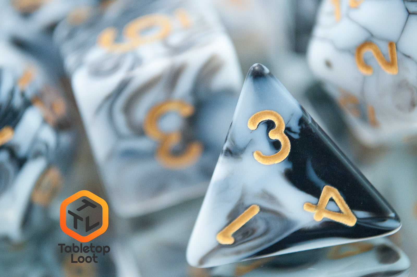 A close up of the D4 from the Rolling Thunder 7 piece dice set from Tabletop Loot with swirls of white, grey, and black resin and gold numbering.