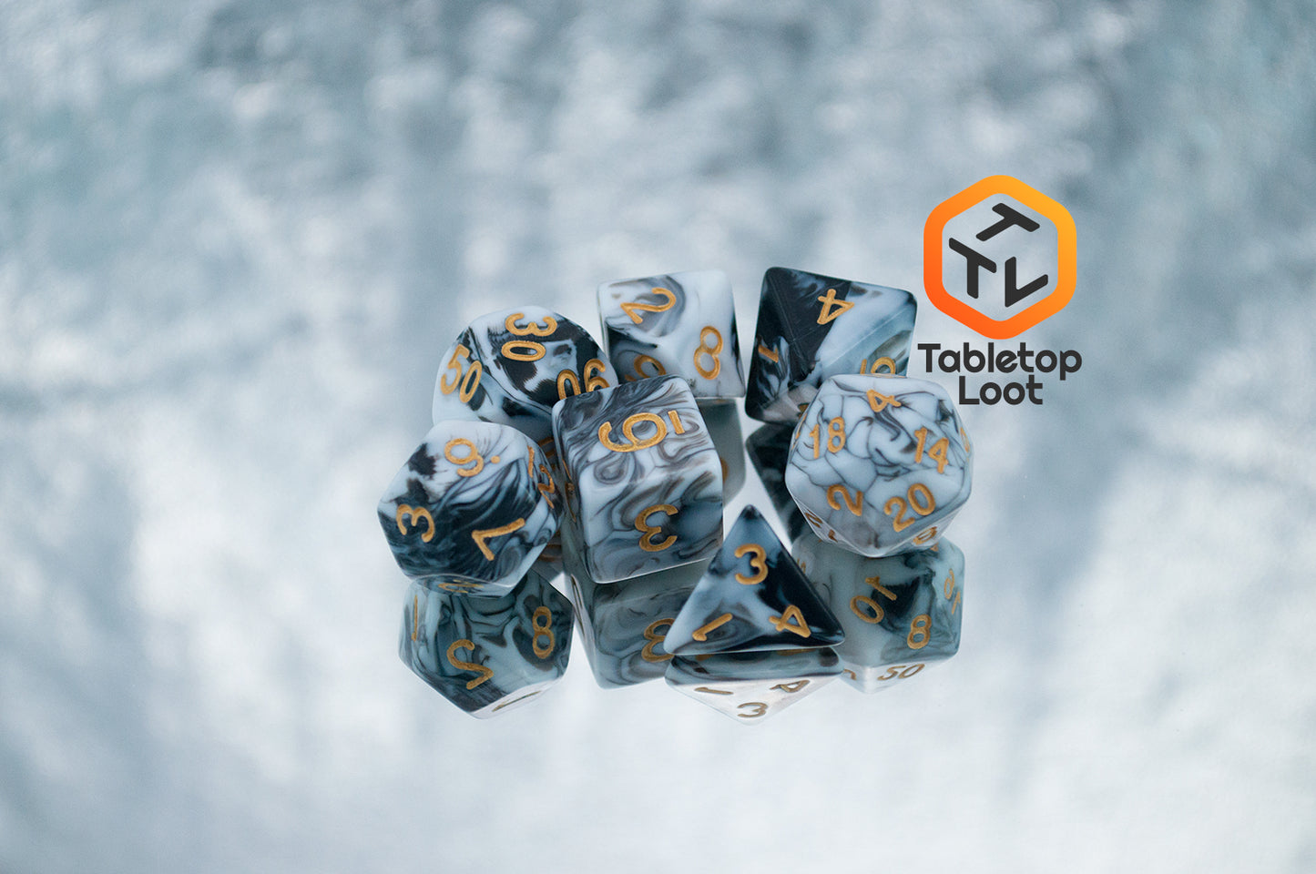 The Rolling Thunder 7 piece dice set from Tabletop Loot with swirls of white, grey, and black resin and gold numbering.