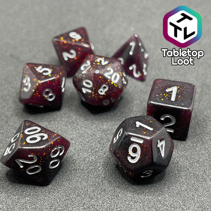 A close up of the Rosavalda 7 piece dice set from Tabletop Loot, ultra dark purple dice with golden glitter and white numbering.