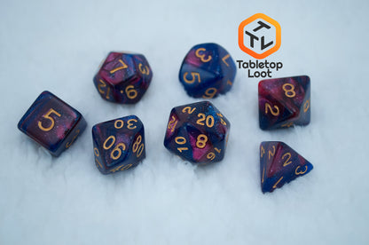 The Rose Galaxy 7 piece dice set from Tabletop Loot with swirls of glittery pink, purple, and blue throughout with gold numbering.