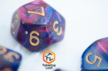 A close up of the D12 from the Rose Galaxy 7 piece dice set from Tabletop Loot with swirls of glittery pink, purple, and blue throughout with gold numbering.
