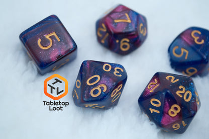 A close up of the Rose Galaxy 7 piece dice set from Tabletop Loot with swirls of glittery pink, purple, and blue throughout with gold numbering.