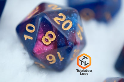 A close up of the D20 from the Rose Galaxy 7 piece dice set from Tabletop Loot with swirls of glittery pink, purple, and blue throughout with gold numbering.