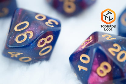 A close up of the Rose Galaxy 7 piece dice set from Tabletop Loot with swirls of glittery pink, purple, and blue throughout with gold numbering.