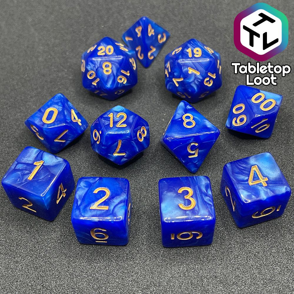 The Royal Sapphire 11 piece dice set from Tabletop Loot with swirls of pearlescent blue and gold numbering.