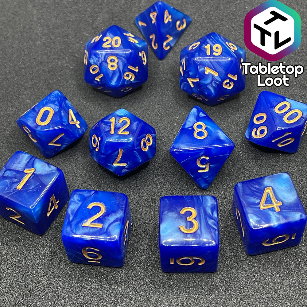 The Royal Sapphire 11 piece dice set from Tabletop Loot with swirls of pearlescent blue and gold numbering.