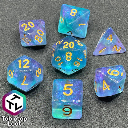 The Shape Water 7 piece dice set from Tabletop Loot with swirls of glittery purple and blue resin and gold numbering.